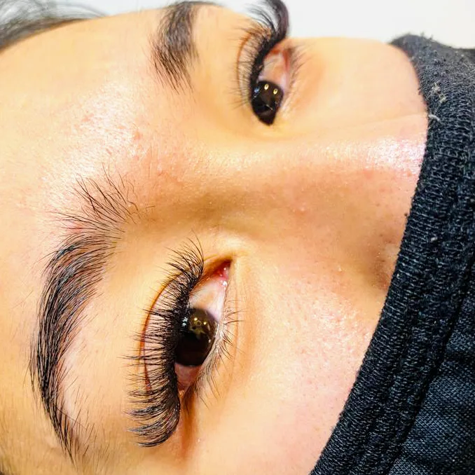 Reclining client's lash extensions from a low side angle, warm skin tones