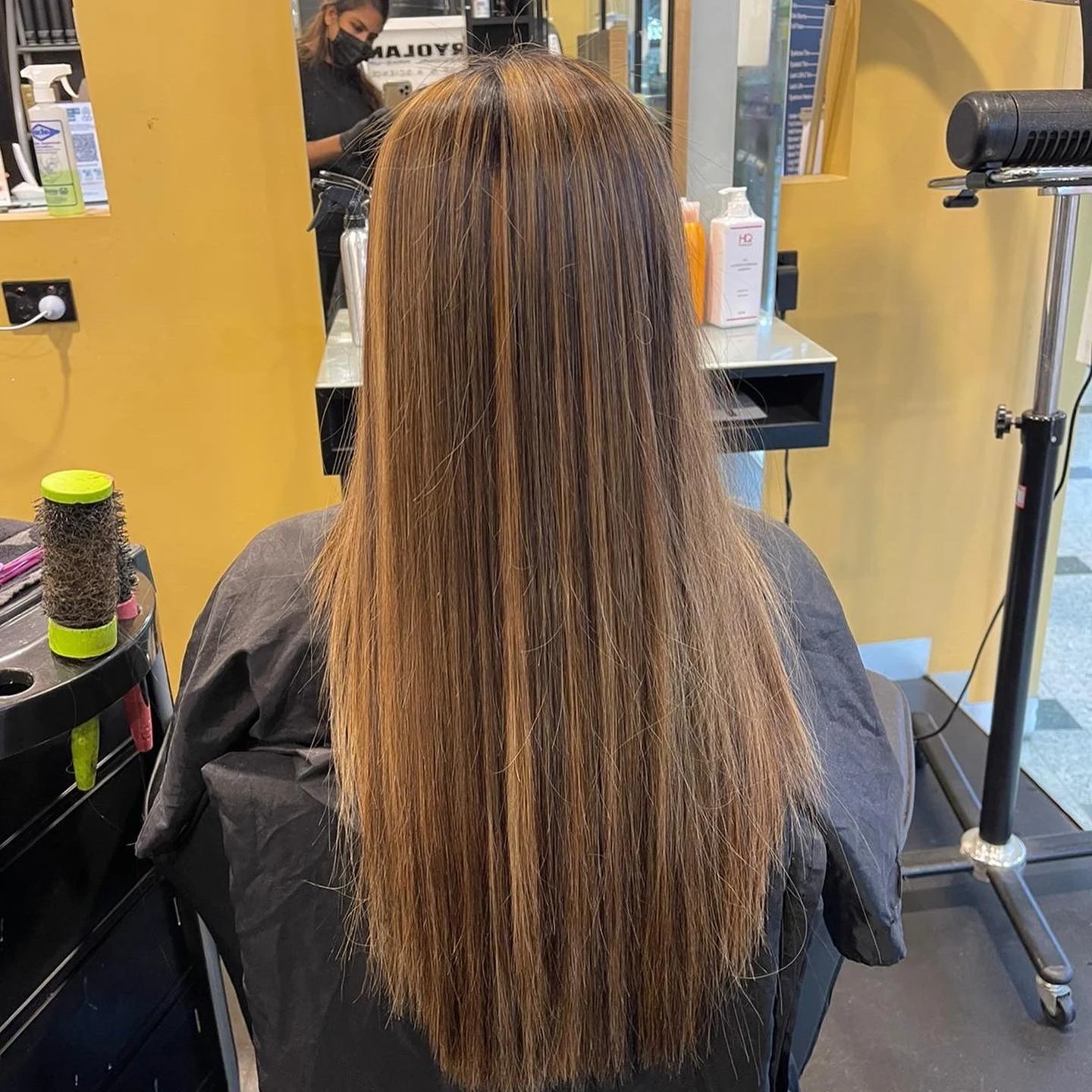 Long warm-caramel balayage finished and combed down a client's back