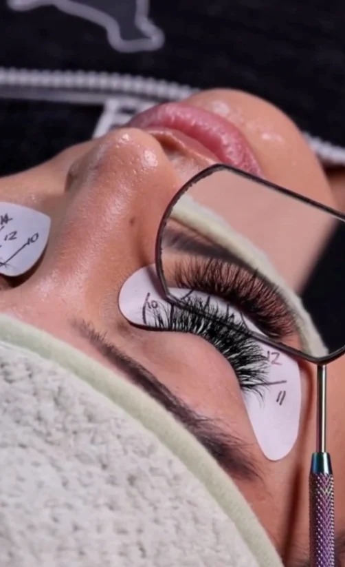 Technician isolating a lash with tweezers over an under-eye gel pad