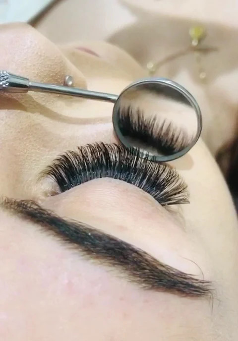 Finished lash set reflected in a dental mirror held to the lash line